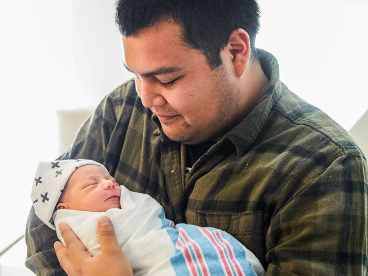 born latino dad holding newborn father care parent coaching families welcome