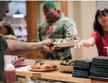 staff member handing plate of food to another staff member