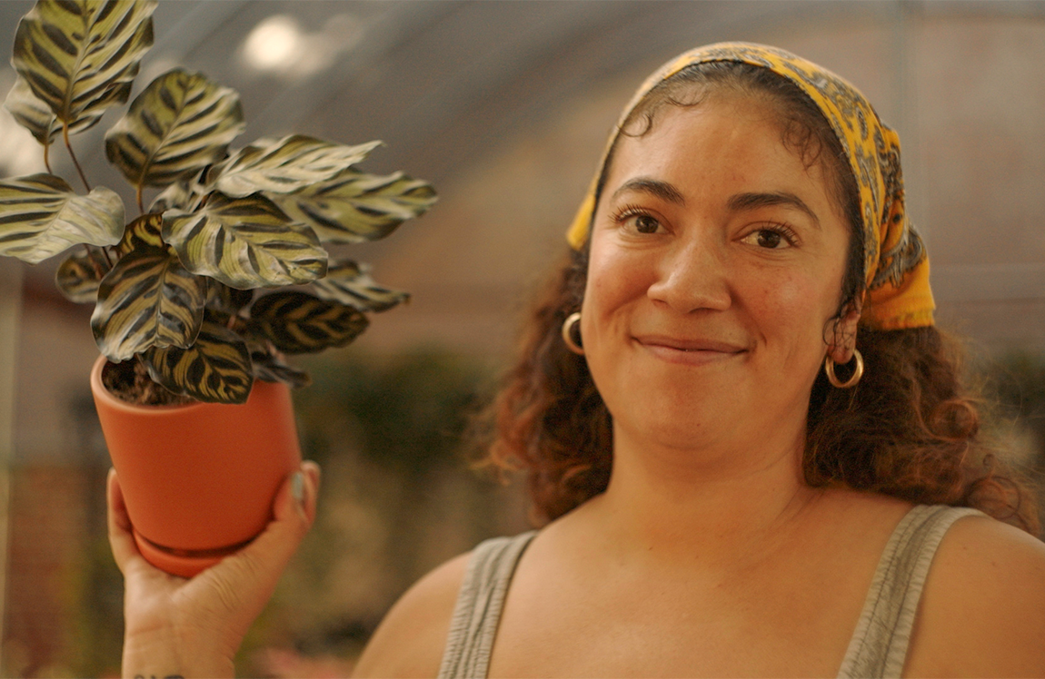 Latina woman smiling holding a plant